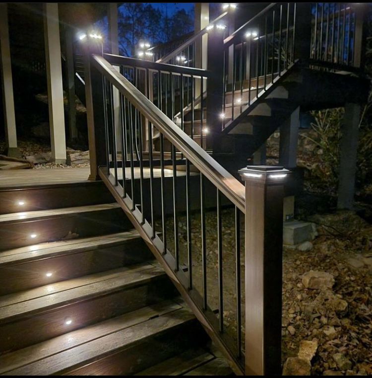 Lit deck stairs with black railing at night