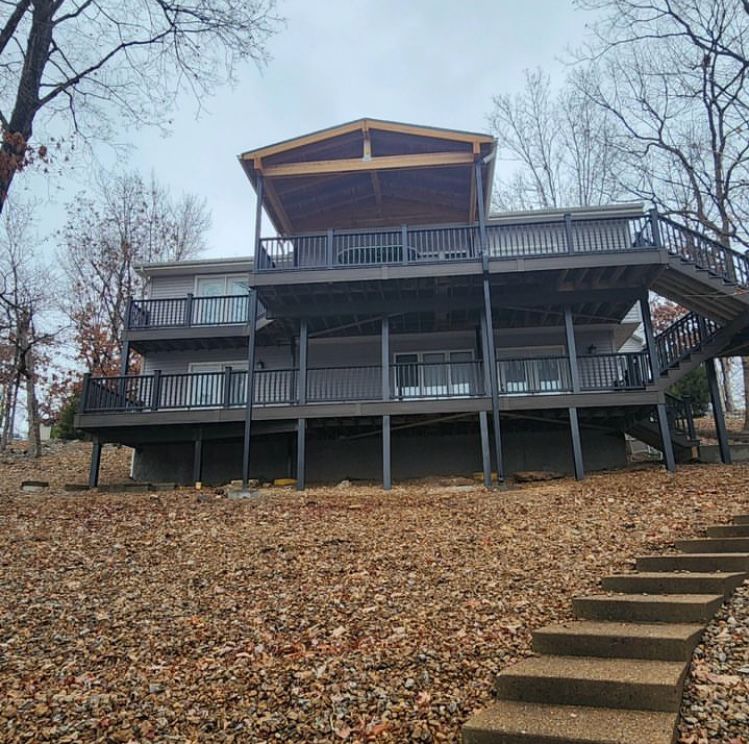Lake home with multi-story decks on a wooded hillside